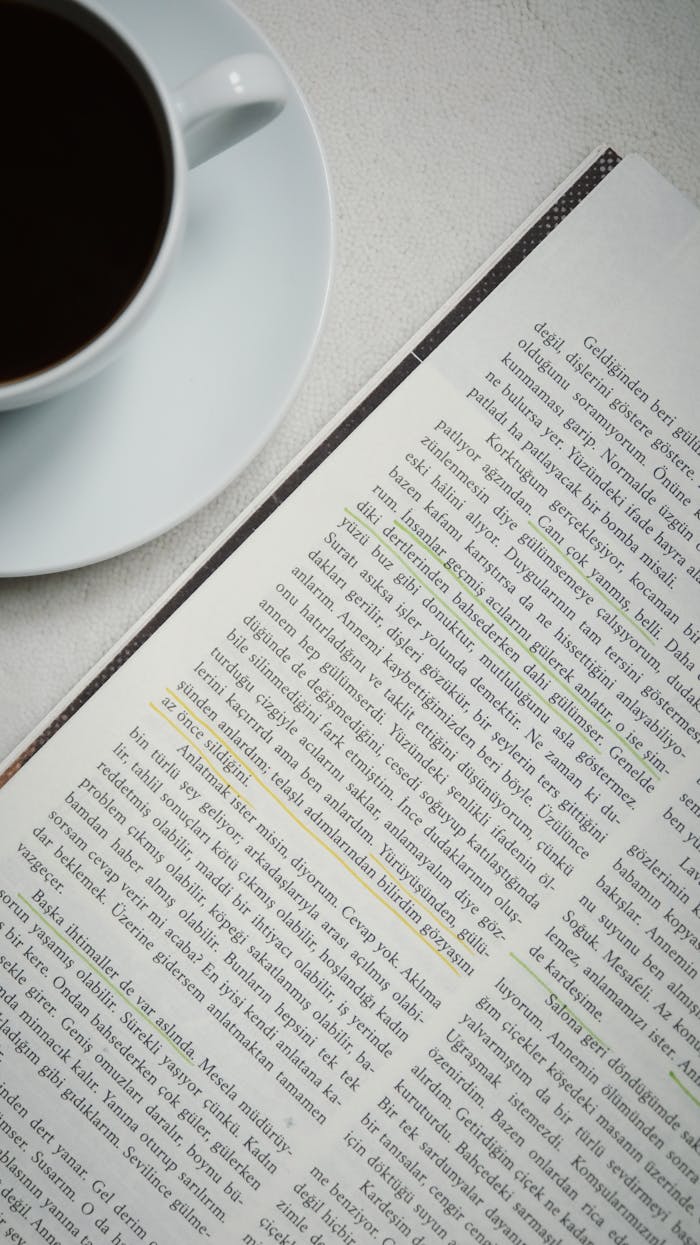 A close-up of an open book with highlighted text beside a cup of coffee on a table.
